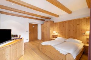a bedroom with wooden walls and a bed with white sheets at Apartments Mupan St. Vigil in San Vigilio Di Marebbe
