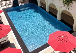 an overhead view of a swimming pool with red umbrellas at Lancaster Tamar Hotel- Hadath in Beirut