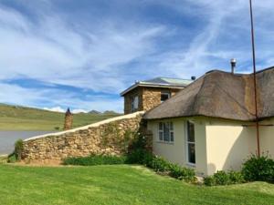 a house with a thatched roof and a stone wall at The Boathouse in Harrismith