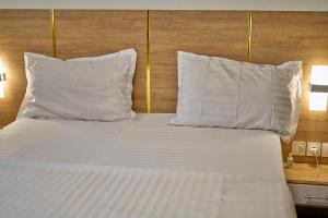 a bed with white pillows and a wooden headboard at RÉSIDENCE Chloé in Bonamoussadi