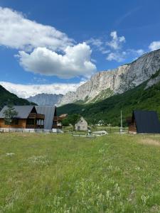 a field with houses and mountains in the background at Komarnica Forest Owl 3 in Šavnik