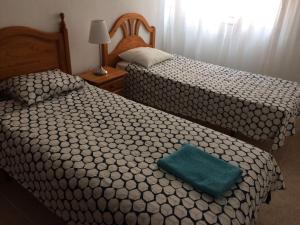 2 łóżka w pokoju hotelowym z zieloną poduszką w obiekcie Apartamento Mateos w Murcji