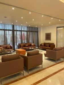 a waiting room with couches and tables and windows at Lancaster Tamar Hotel- Hadath in Beirut