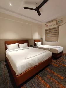 two beds in a hotel room with a ceiling fan at SW Hotel MG Road in Bangalore +31 photos