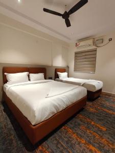 two beds in a bedroom with a ceiling fan at SW Hotel MG Road in Bangalore