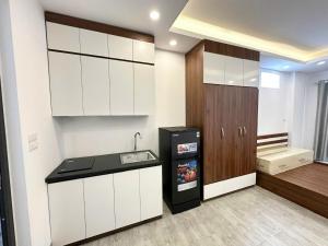 a kitchen with white cabinets and a black refrigerator at 25House Cozy Apartment near West Lake & Airport in Hanoi