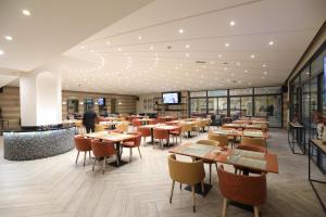 a restaurant with tables and chairs and a person in the background at Lancaster Tamar Hotel- Hadath in Beirut