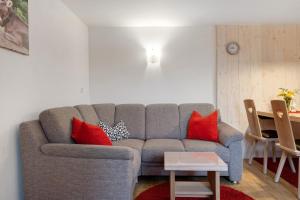 a living room with a gray couch with red pillows at Süßen Häusle in Breitnau +31 photos