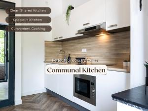 a kitchen with white walls and wooden floors at Cozy Room w Shared Kitchen, Fast WiFi Near Station in Tilburg