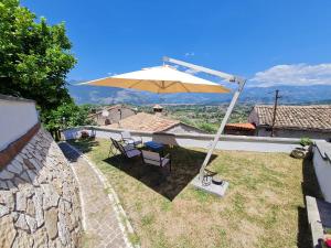 eine Terrasse mit Sonnenschirm, Tisch und Stühlen in der Unterkunft Il Camerone in Isola del Liri