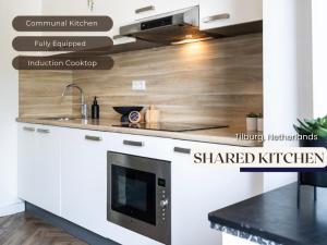 a kitchen with white cabinets and a black counter top at Budget room w kitchen, Station close, Wifi Access in Tilburg