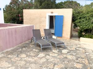 two chairs sitting in front of a building with a blue door at CAN TONI DEN MESTRE in Cala Saona +7 photos