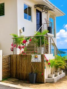a house with potted plants in front of a fence at Sunset View Self Catering in Anse Boileau