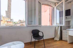 a black chair sitting in a room with windows at Asinelli, Bologna by Short Holidays in Bologna