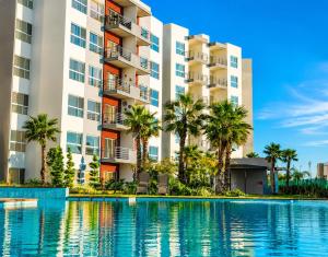 aominium building with a swimming pool and palm trees at Rosarito Papas & ocean view Condo in Rosarito