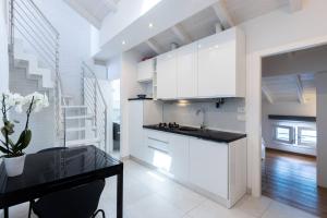 a kitchen with white cabinets and a black counter top at Asinelli, Bologna by Short Holidays in Bologna