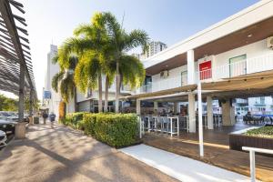 a street with palm trees and a building at Nightcap at the Cavenagh in Darwin