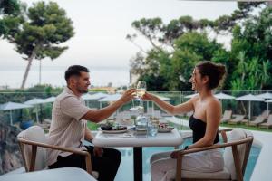 a man and woman sitting at a table drinking wine at Radisson Hotel Cannes Seaside in Cannes +57 photos