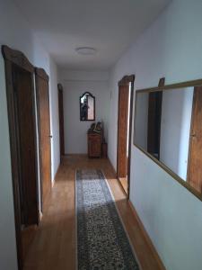 a hallway with wooden floors and white walls and a mirror at VRATA IGMANa in Hadžići
