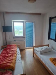 two beds in a room with two windows at VRATA IGMANa in Hadžići