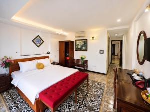 a bedroom with a large white bed with a red bench at Hanoi Luxury Hotel - Old Quarter in Hanoi
