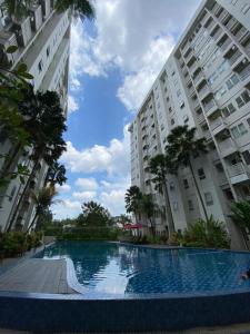 a swimming pool in front of two large buildings at Malioboro City Apartement by Dev's Room in Seturan