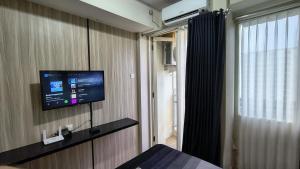 a room with a flat screen tv on a wall at Malioboro City Apartement by Dev's Room in Seturan
