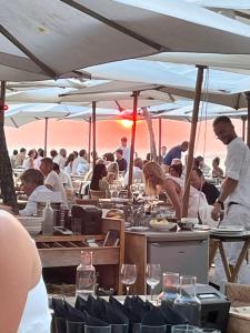 a group of people sitting at tables in a restaurant at Maison Albatros in Pyla-sur-Mer