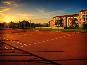 a tennis court with the sun setting in the background at Jacuzzi, massage et plage ! in Fréjus