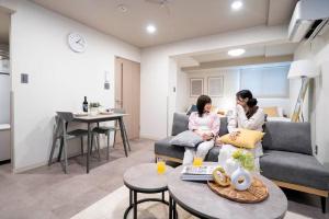 two women sitting on a couch in a living room at Lotus south in Sapporo