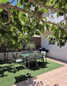 a patio with a table and chairs under a tree at Aura Seaside Afrathias in Kalamaki