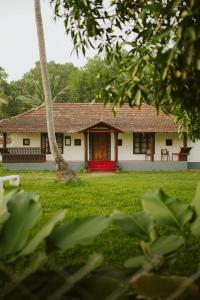 a house with a red door in a yard at Alleppey Backwater Resort in Alleppey