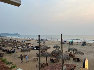 a beach with people and umbrellas and the ocean at Cassa ff guesthouse in Palolem