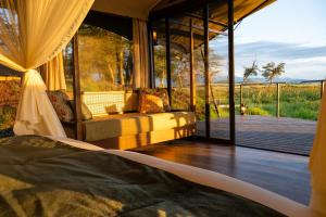 a room with a bed and a balcony with a view at Soroi Amboseli in Amboseli