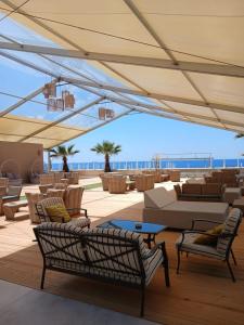 an outdoor patio with couches and chairs and the ocean at Didimos Resort in Reggio di Calabria
