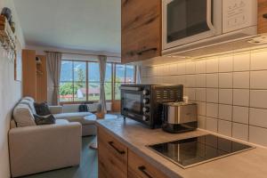 a kitchen with a microwave and a living room at Apartment BergStyle in Pfronten