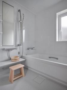 a bathroom with a tub and a toilet and a stool at Adagio Retreat Tokachidake in Biei +25 photos