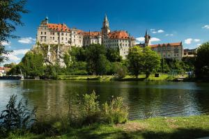 a large castle on a hill next to a body of water at Apartment am Schloss in Sigmaringen