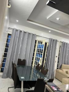 a dining room with a table and chairs and windows at TGS home in Lomé +4 photos