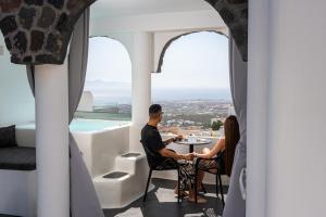 a couple sitting at a table in a room with a view at Black Shade Suite in Fira
