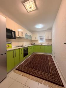 a kitchen with green cabinets and a rug on the floor at Vila Noor Sarajevo in Sarajevo
