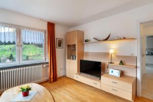 a living room with a large television and a table at Haus Am Schroffen in Ottenhöfen