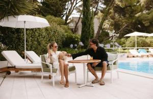 a man and woman sitting at a table with a dog at Maestral Adults Exclusive Hotel in Brela +50 photos