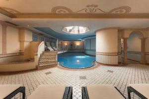 ein Schwimmbecken in einem großen Raum mit einer Treppe in der Unterkunft Hotel & Residence Rose in Sterzing