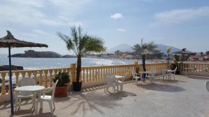 een balkon met tafels en stoelen en een strand bij Bahía - 30º hotels in Puerto de Mazarrón