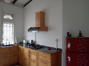 a kitchen with a stove and a red refrigerator at Sobasee Holiday Bungalow in Kandy