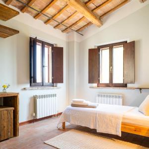 a bedroom with a bed and two windows at Rifugio Vita Luminosa in Montecarotto