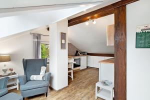 a living room with a blue chair and a kitchen at Schwarzwaldtani - Dörfle in Weier