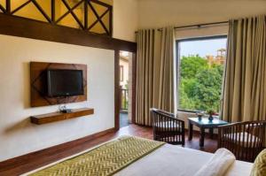 a bedroom with a bed and a television and a table at Sunday Alaya Resort by CheckIn, Jim Corbett in Belparāo
