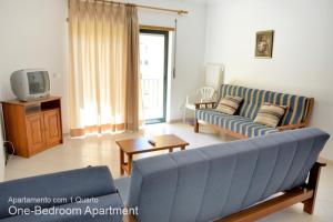 sala de estar con sofá azul y TV en Akisol Armação Pera Beach, en Armação de Pêra